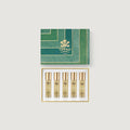 Set of five gold bottles with a green Creed box on a light gray background