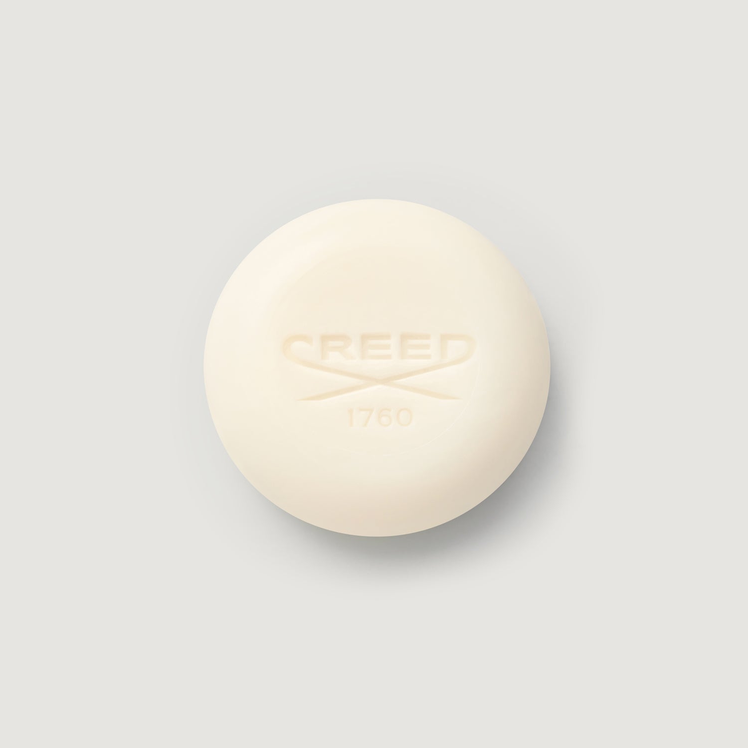 Cream-colored bar of soap with 'CREED' branding on a light gray background